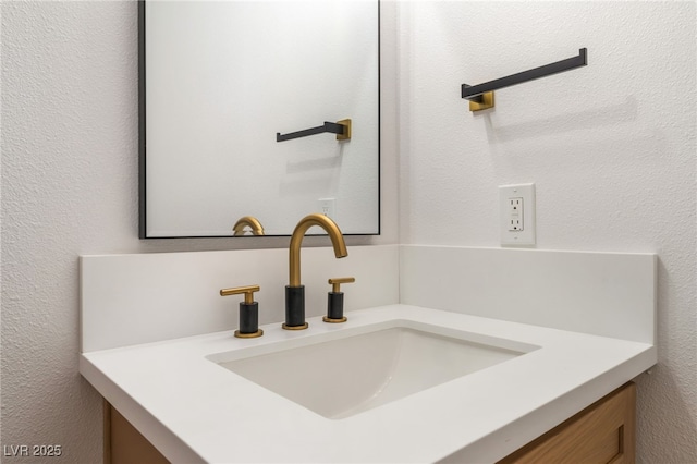 bathroom view of vanity and a textured wall