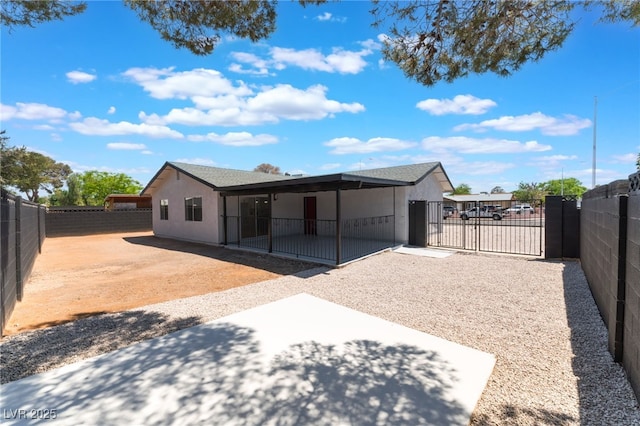 rear view of house featuring a fenced backyard, a gate, stucco siding, and a patio area