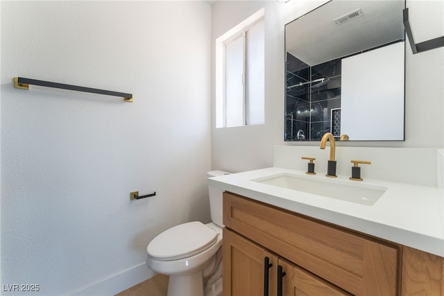 bathroom with toilet, vanity, tiled shower, and baseboards