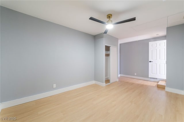 unfurnished room with attic access, a ceiling fan, light wood finished floors, and baseboards