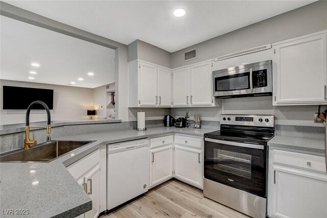 2224 Lucerne Ct, Henderson, NV 89014 - kitchen featuring appliances with stainless steel finishes, a sink, light wood-type flooring, white cabinetry, and recessed lighting