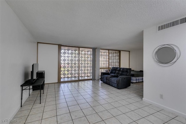 living room featuring a textured ceiling, light tile patterned flooring, and baseboards