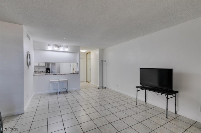 living area featuring a textured ceiling, baseboards, and light tile patterned floors