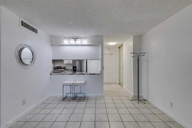 kitchen featuring stainless steel appliances, a textured ceiling, white cabinetry, a peninsula, and a breakfast bar