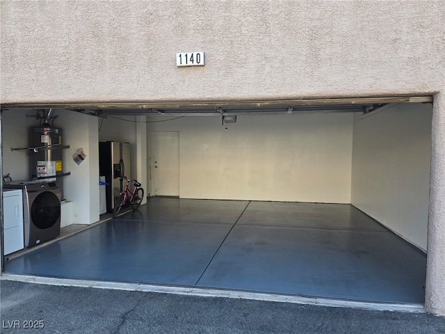 garage with washing machine and clothes dryer and strapped water heater