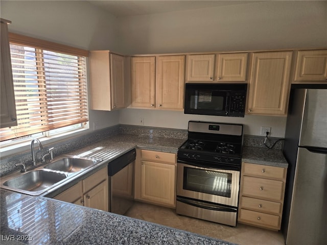 kitchen with appliances with stainless steel finishes, light brown cabinets, a sink, dark countertops, and light tile patterned floors