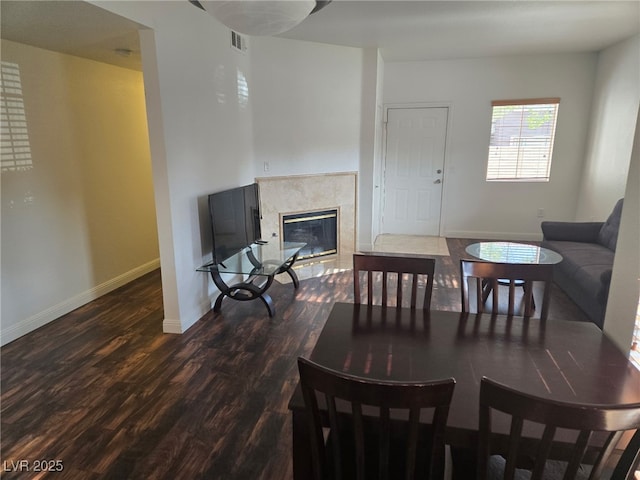 dining area with dark wood-style flooring, a fireplace, and baseboards