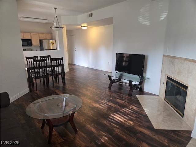 living room with wood finished floors, a tile fireplace, and baseboards