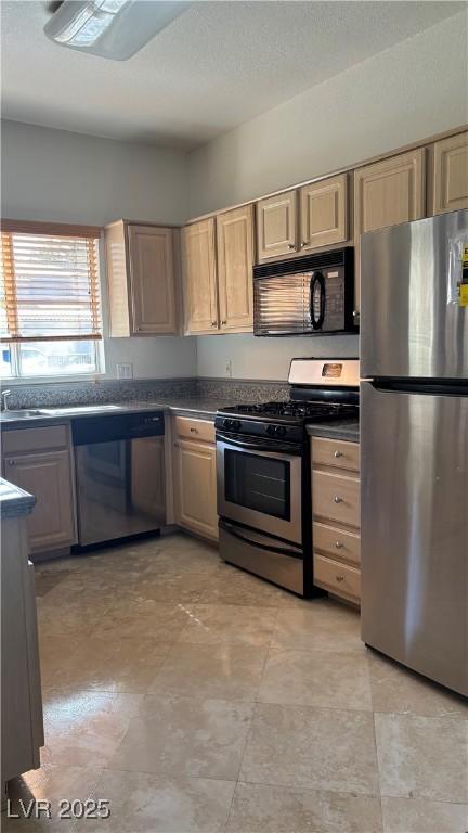 kitchen with appliances with stainless steel finishes, light brown cabinets, and dark countertops