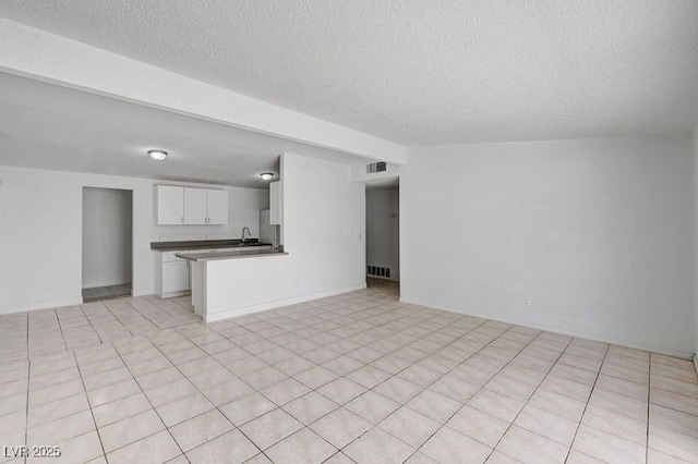 unfurnished living room featuring a textured ceiling and a sink