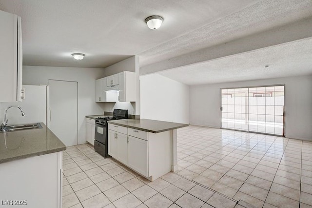 kitchen featuring black gas range, a sink, open floor plan, freestanding refrigerator, and light tile patterned flooring