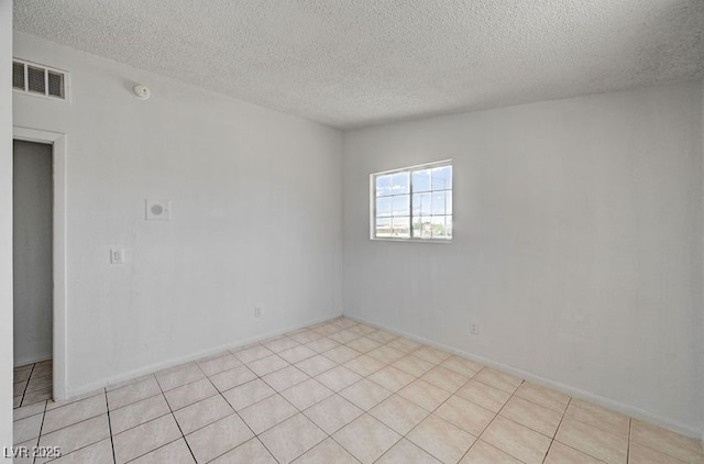 spare room featuring a textured ceiling, a smoke detector, and light tile patterned flooring