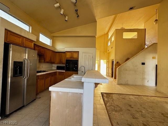 529 Rancho Del Mar Way N, Las Vegas, NV 89031 - kitchen with stainless steel fridge with ice dispenser, light tile patterned floors, brown cabinetry, a sink, and high vaulted ceiling