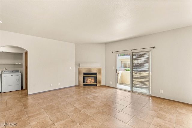 4830 Grey Wolf Ln Unit 104, Las Vegas, NV 89149 - unfurnished living room with washer / dryer, arched walkways, light tile patterned flooring, and a tile fireplace