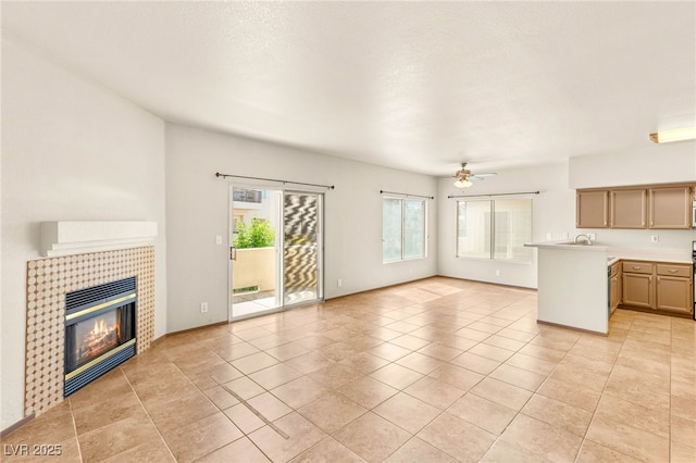 4830 Grey Wolf Ln Unit 104, Las Vegas, NV 89149 - unfurnished living room with ceiling fan, a fireplace, light tile patterned floors, and a sink