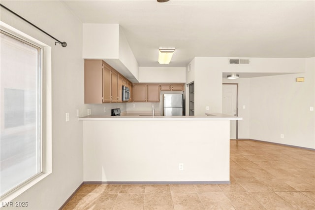4830 Grey Wolf Ln Unit 104, Las Vegas, NV 89149 - kitchen with stainless steel appliances, light countertops, a peninsula, brown cabinets, and baseboards