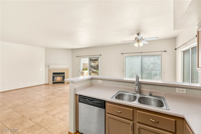 4830 Grey Wolf Ln Unit 104, Las Vegas, NV 89149 - kitchen featuring stainless steel dishwasher, a sink, ceiling fan, light tile patterned floors, and a brick fireplace
