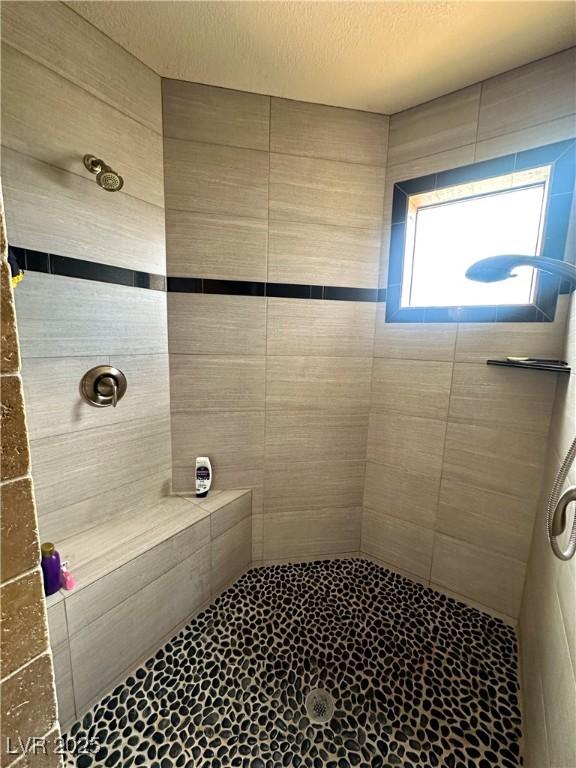 bathroom with a tile shower, a textured ceiling, and tile patterned flooring
