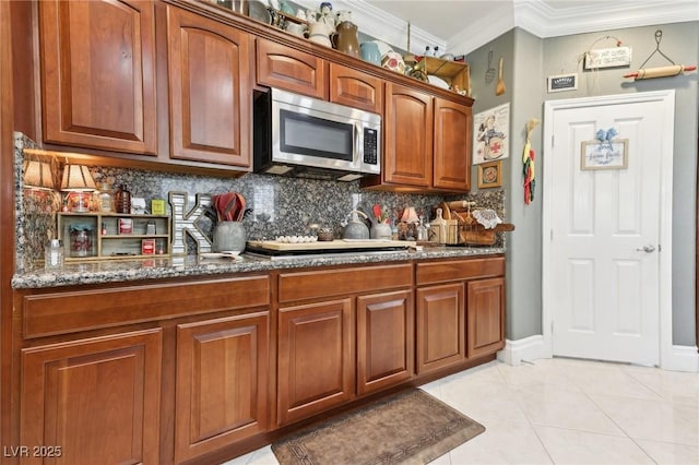 7301 Heggie Ave, Las Vegas, NV 89131 - kitchen with stainless steel microwave, decorative backsplash, crown molding, dark stone counters, and light tile patterned floors
