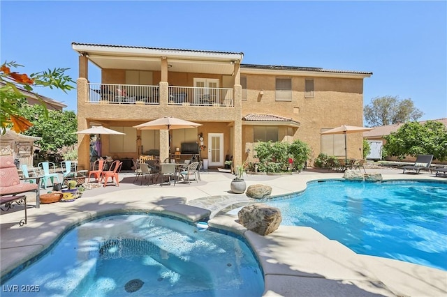 7301 Heggie Ave, Las Vegas, NV 89131 - back of property with a balcony, an in-ground hot tub, a patio, stucco siding, and a tiled roof