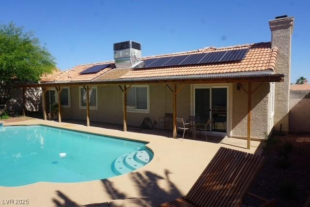back of property featuring a chimney, stucco siding, central AC unit, and roof mounted solar panels