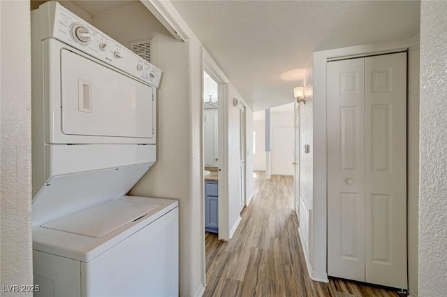 washroom featuring estacked washer and dryer and wood finished floors