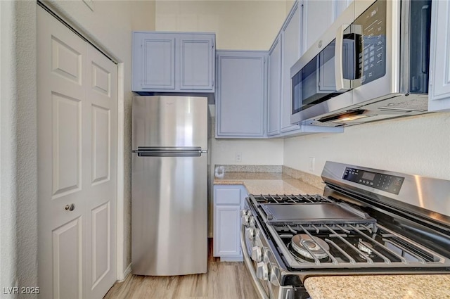 kitchen featuring stainless steel appliances, light countertops, and light wood-style floors