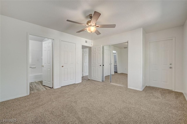 unfurnished bedroom featuring carpet, baseboards, ensuite bathroom, and a ceiling fan