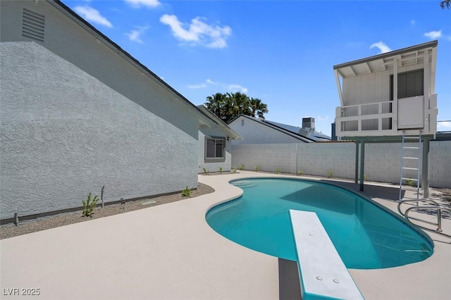 view of swimming pool featuring a patio area, a diving board, and a fenced backyard