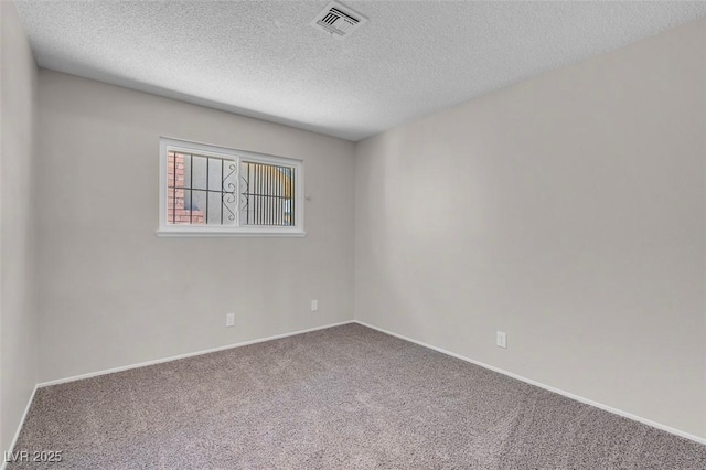 carpeted empty room featuring a textured ceiling and baseboards