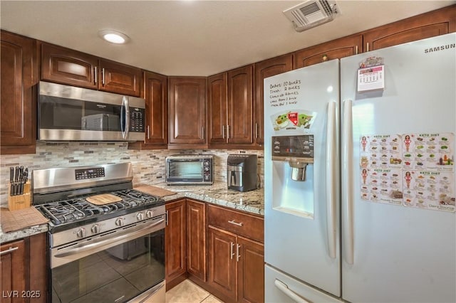824 Schooner Dr, Henderson, NV 89015 - kitchen with stainless steel appliances, light stone countertops, tasteful backsplash, and light tile patterned floors