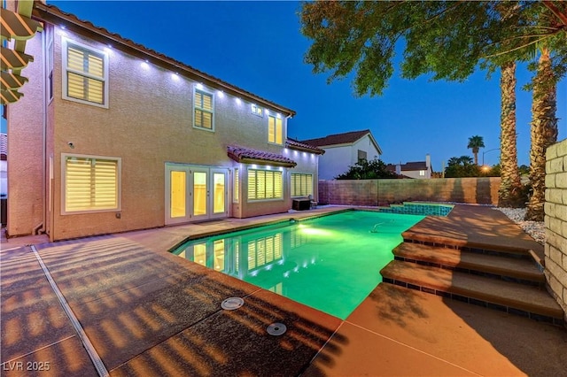 pool at night featuring a fenced backyard, a patio, central air condition unit, and french doors