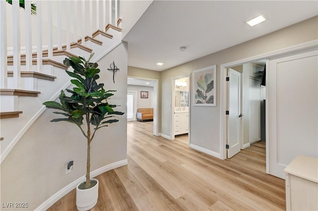 hallway featuring wood finished floors, stairs, baseboards, and recessed lighting
