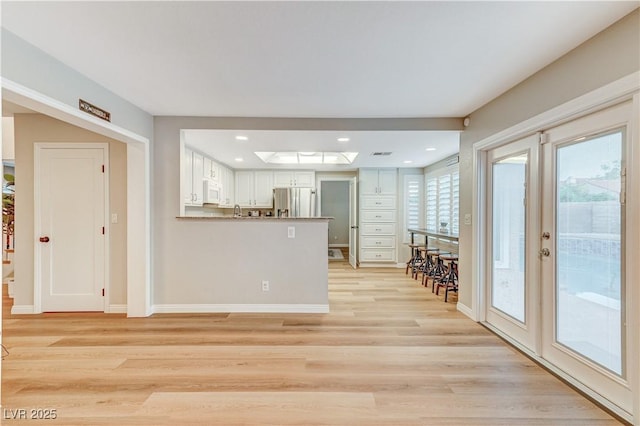 kitchen with stainless steel fridge, white microwave, light wood-style floors, white cabinets, and recessed lighting