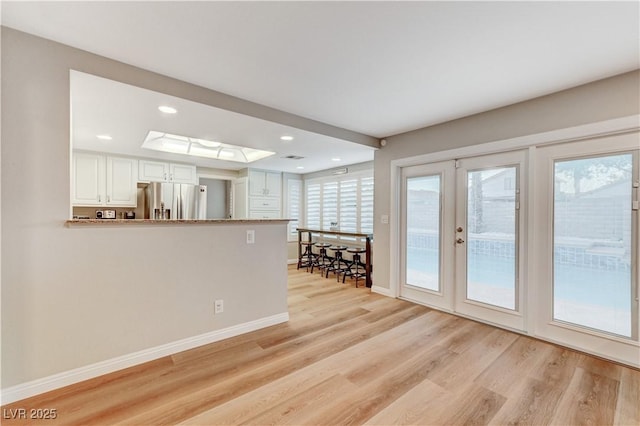unfurnished living room with light wood finished floors, french doors, baseboards, and recessed lighting