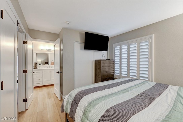 bedroom featuring light wood finished floors, a closet, and ensuite bathroom