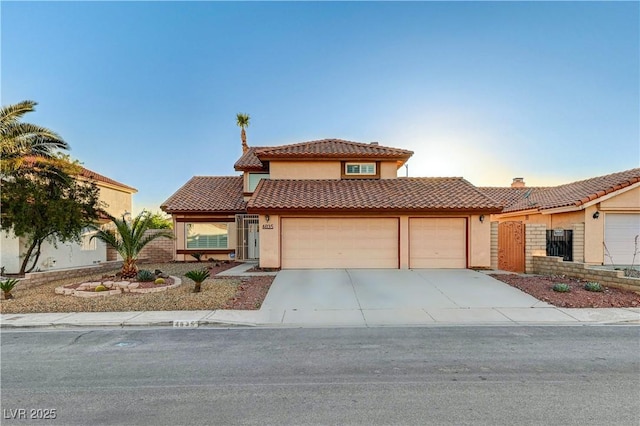 mediterranean / spanish home featuring an attached garage, stucco siding, a tile roof, driveway, and fence