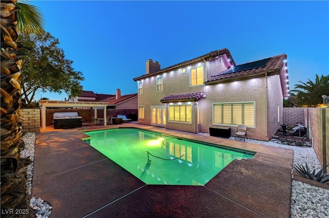 rear view of property with a fenced backyard, a patio, a hot tub, stucco siding, and a chimney