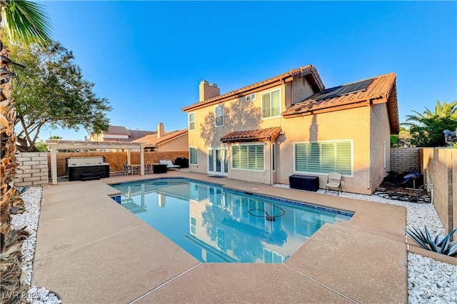 rear view of property with a chimney, a fenced backyard, stucco siding, a patio area, and a tiled roof