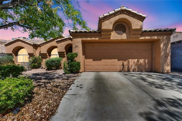 819 Arrowhead Trl, Henderson, NV 89002 - mediterranean / spanish-style home with a tiled roof, stucco siding, an attached garage, and driveway