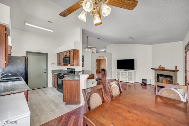 819 Arrowhead Trl, Henderson, NV 89002 - dining area featuring ceiling fan, lofted ceiling, arched walkways, light wood finished floors, and a glass covered fireplace