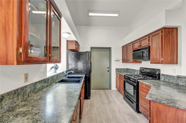 819 Arrowhead Trl, Henderson, NV 89002 - kitchen with black appliances, a sink, light wood-style flooring, glass insert cabinets, and dark countertops