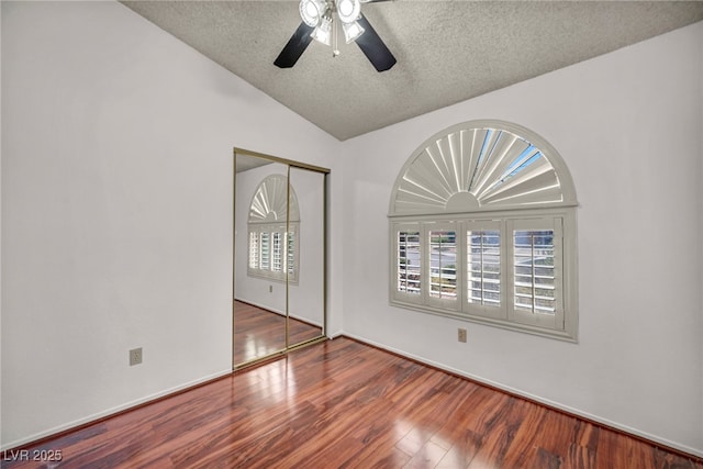 819 Arrowhead Trl, Henderson, NV 89002 - unfurnished bedroom featuring a textured ceiling, a closet, multiple windows, wood finished floors, and vaulted ceiling