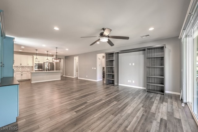 unfurnished living room with a ceiling fan, baseboards, recessed lighting, and dark wood-style floors