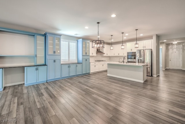 kitchen with appliances with stainless steel finishes, light countertops, decorative backsplash, recessed lighting, and pendant lighting