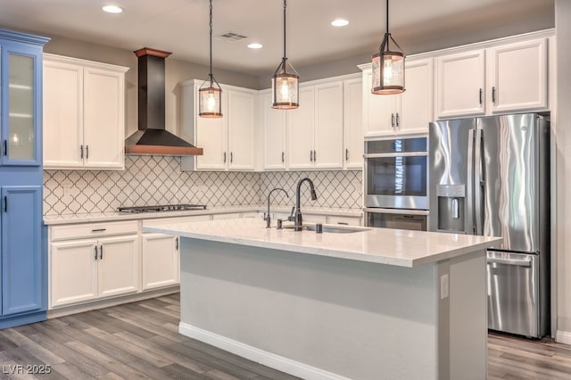 kitchen with stainless steel appliances, a sink, wall chimney range hood, white cabinetry, and dark wood-type flooring