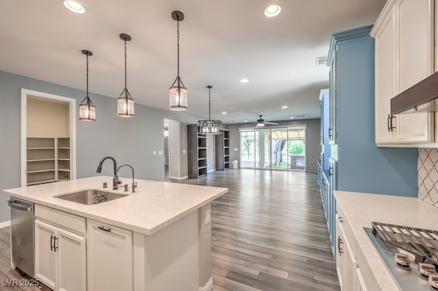 kitchen featuring a sink, a ceiling fan, stainless steel appliances, dark wood-style floors, and a center island with sink