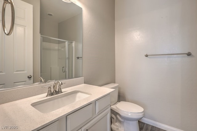 full bathroom featuring a stall shower, toilet, vanity, and wood finished floors