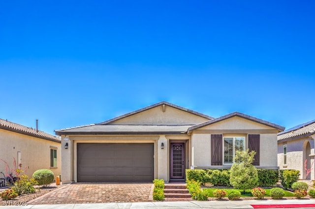 single story home with decorative driveway, an attached garage, stucco siding, and a tiled roof