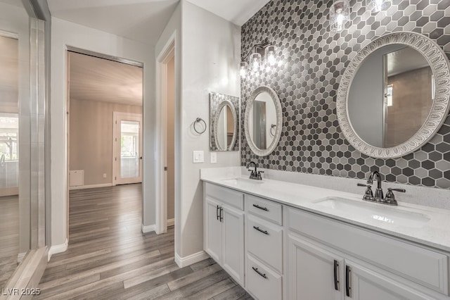 full bathroom featuring wood finished floors, tasteful backsplash, baseboards, and double vanity